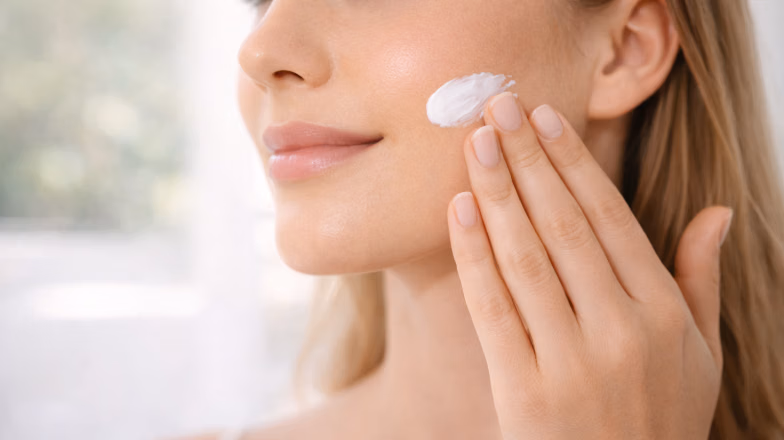 Close-up of a woman applying face cream or primer to prep skin before base makeup