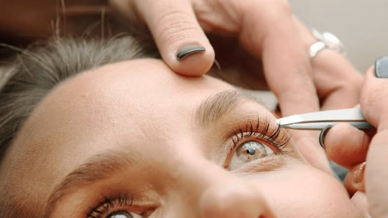 Lash technician separating and shaping eyelashes during lash lift procedure