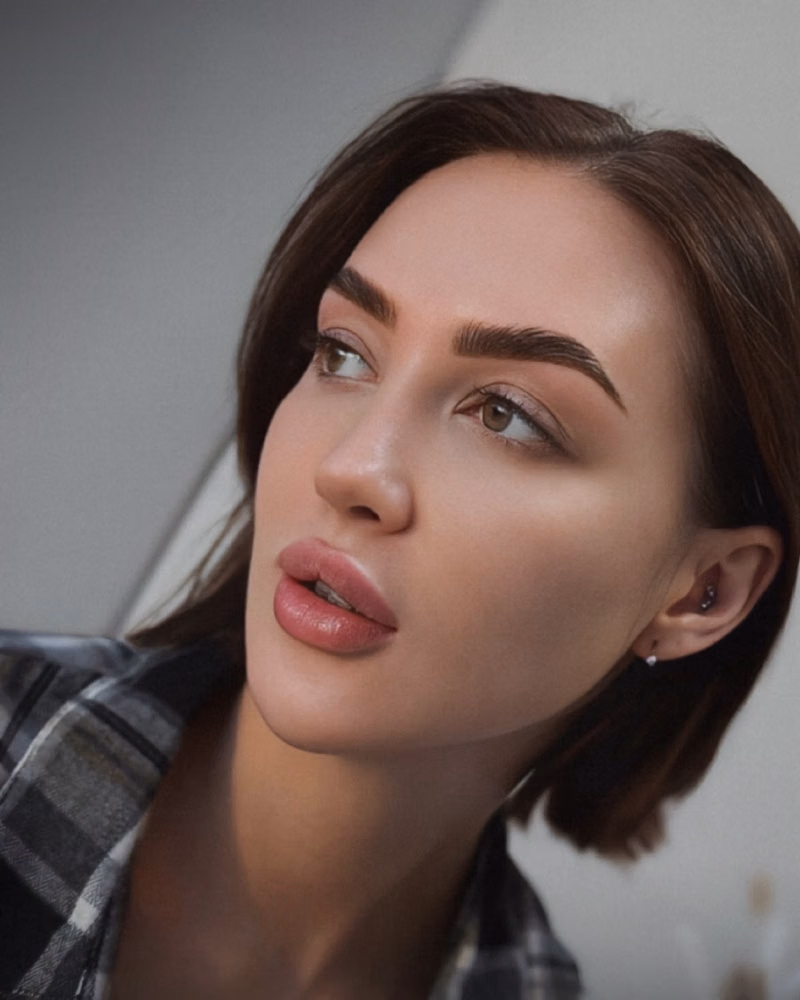 Side-angle portrait highlighting bold, defined brows after brow threading and lamination, with a sleek lifted shape and polished finish