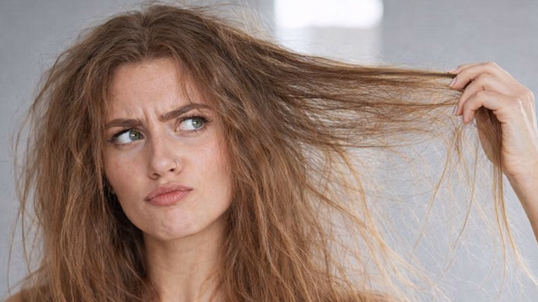 Woman pulling a section of tangled hair, showing concern about hair breakage and shedding