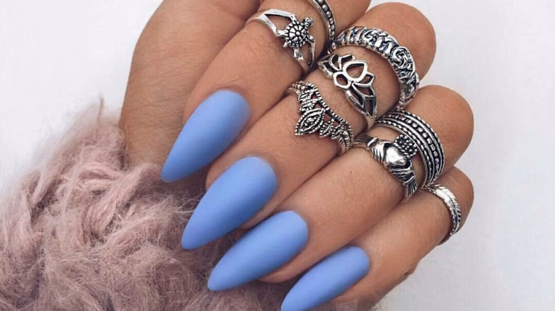 Matte blue acrylic nails in long stiletto shape with statement rings