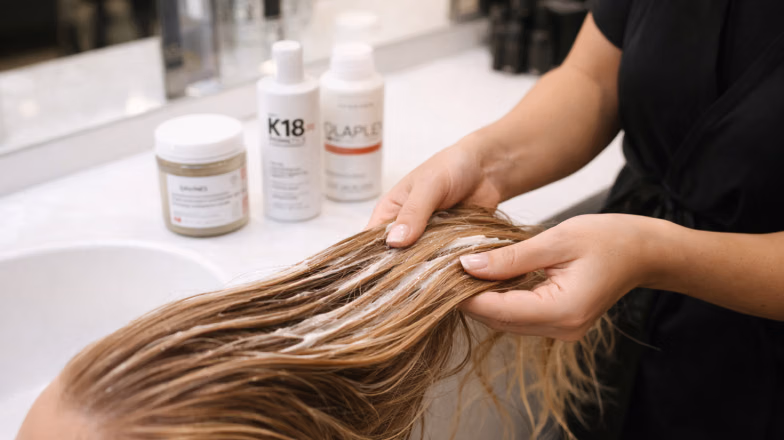 Stylist examining wet hair strands at a salon to assess breakage and overall hair condition