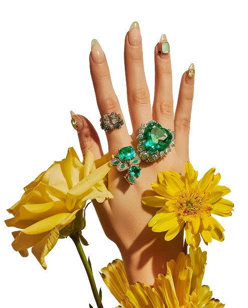 Elegant hand with decorative manicure, green gemstone rings and floral elements, showcasing creative nail art services in Dubai studio
