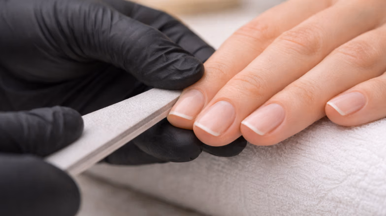 Nail technician filing the free edge of natural nails to prevent splitting and peeling