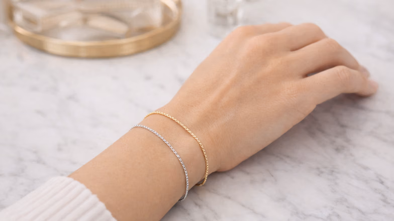 Hand with gold and silver bracelets demonstrating jewelry test for identifying skin undertone