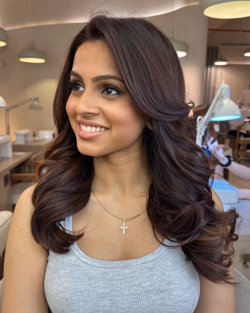Woman with glossy, voluminous brunette hair showcasing the results of a revitalizing scalp treatment