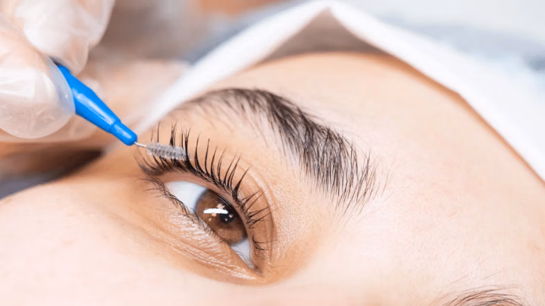 Applying solution to eyelashes during lash lift treatment in a beauty salon