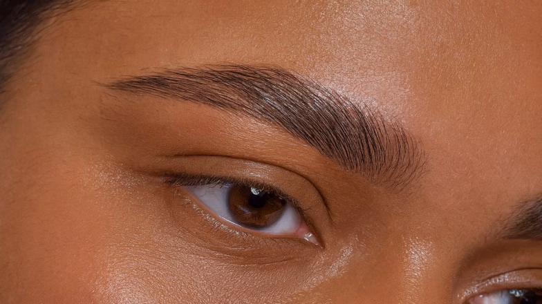 Applying solution to eyebrows during brow lamination procedure in salon