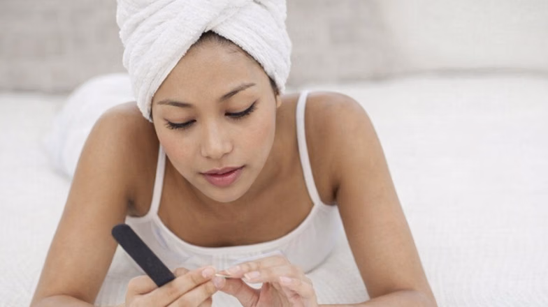 Woman caring for her nails at home, showing concern about nail splitting and damage